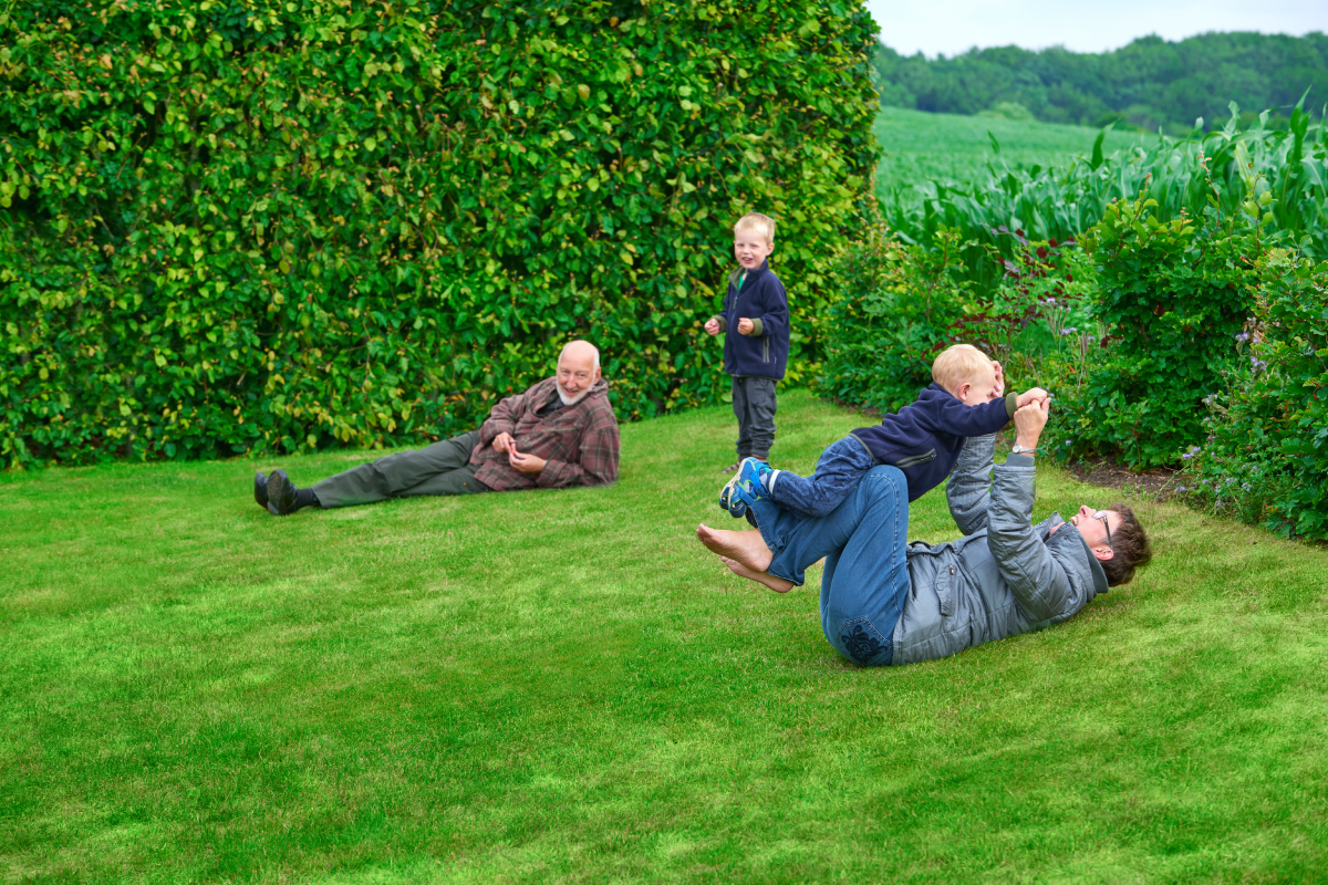 Familie med flere generationer, der leger på græsset