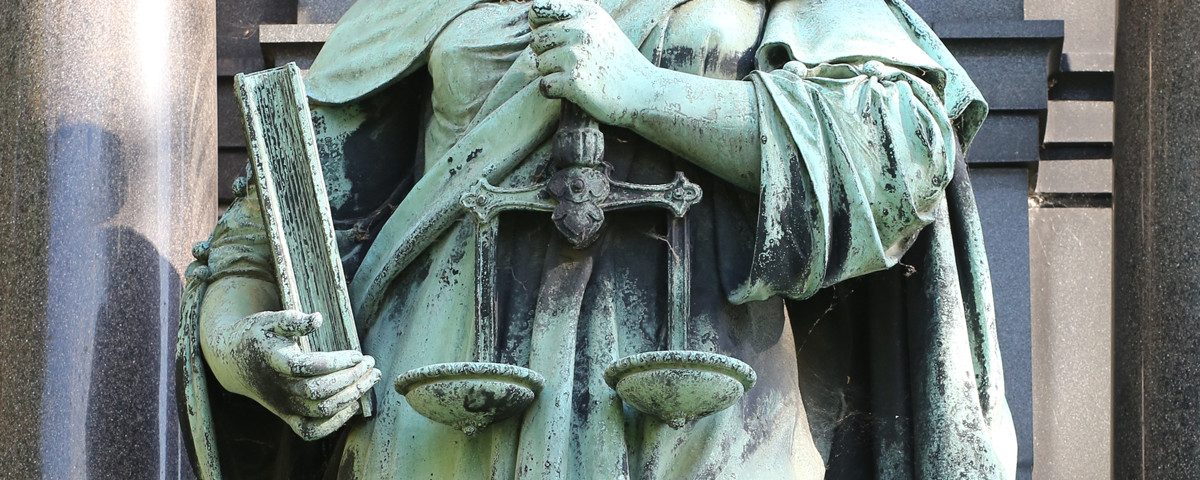 En statueholder en vægt med to skåle som symbol på retfærdighed.