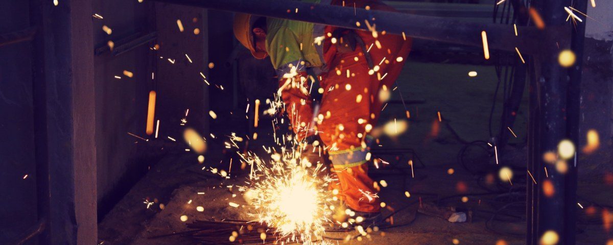 En person arbejder med en vinkelsliber, der skaber gnister på gulvet.