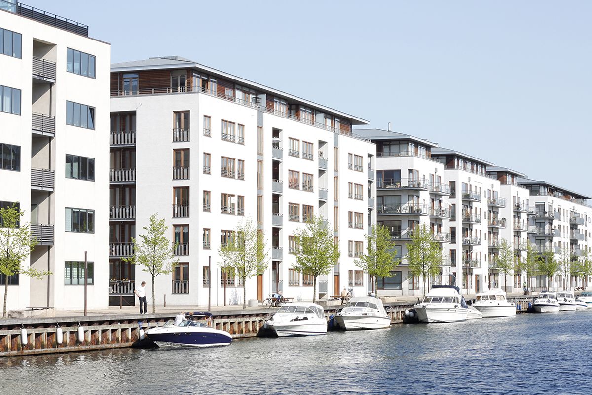 Moderne lejlighedsbygninger langs en kanal med både fortøjet.