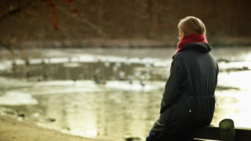 Kvinde sidder ved en sø.